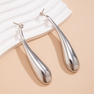 Détail d'une boucle d'oreille goutte polie avec cristal sur un support à vagues douces