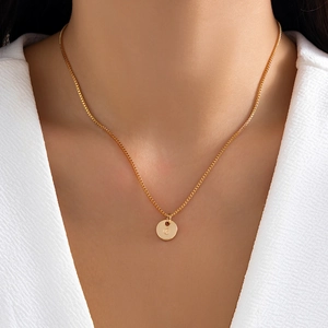 Detailed close-up of a gold round disk pendant featuring an engraved letter C on a box chain