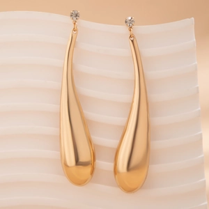 Gros plan sur des boucles d'oreilles goutte dorées avec un petit strass scintillant