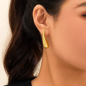Vue rapprochée d'une boucle d'oreille goutte dorée avec surface métallique miroir