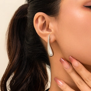 Gros plan d'un mannequin portant des boucles d'oreilles larmes en argent poli punk