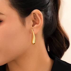 Gros plan sur une boucle d'oreille goutte d'eau dorée minimaliste au fini poli brillant