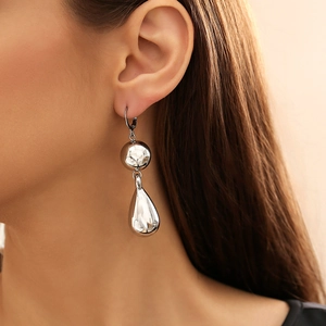 Orecchini a goccia e sfere in metallo argento lucido su modella con stile minimalista