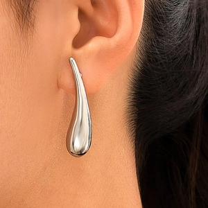 Gros plan détaillé d'une boucle d'oreille goutte en argent poli sur un modèle