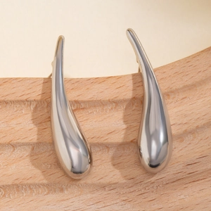 Vue macro de boucles d'oreilles goutte d'argent avec finition miroir sur support bois