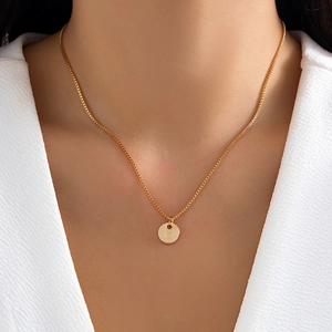 Detailed close-up of a golden box chain necklace featuring a minimalist letter K round pendant