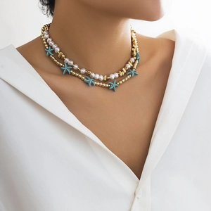 Close-up of double-layer necklace with blue starfish charms and white beads on a model