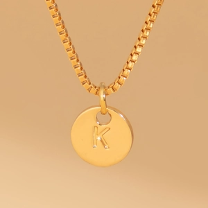 Macro shot of gold-plated pendant necklace with engraved letter K and box chain