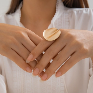 Close-up of a large golden irregular petal ring with matte texture on a female hand