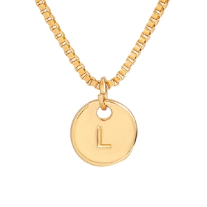 Macro detail of gold round pendant with letter L engraving on a classic box chain