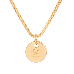 Macro view of gold round pendant with engraved letter M on a polished box chain
