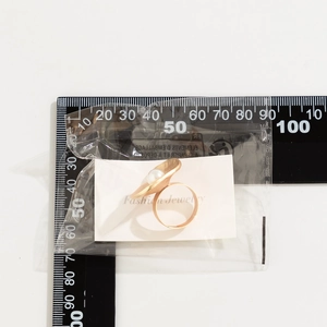 Detailed scale measurement of gold petal ring with pearl center on ruler