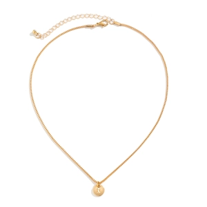 Close-up of golden necklace showing engraved letter N on circular pendant and lobster clasp