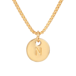 Detailed macro of gold round pendant necklace featuring an engraved letter N on box chain