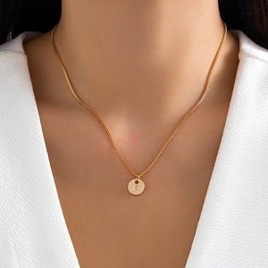 Macro shot of a gold round pendant with letter P engraving on a box chain for women