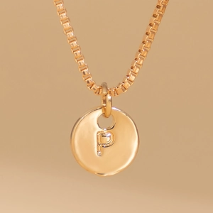 Close-up of gold box chain necklace with a thick round letter P pendant