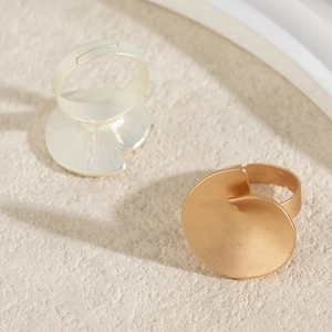 Macro detail of irregular wave disc metal rings in matte gold and silver finish