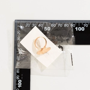 Macro detail of gold-plated round base ring setting on a white display card with scale