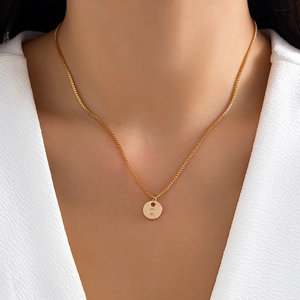 Close-up of minimalist gold letter Q pendant necklace on a woman's neck