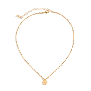 Macro detail of gold round pendant with letter R engraving and square link chain