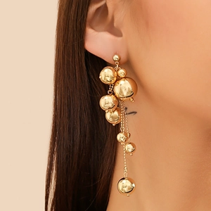 Détail de boucles d'oreilles pampilles dorées à perles brillantes sur mannequin