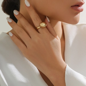 Polished gold pebble-shaped ring on model, showing sculpture-style minimalist design