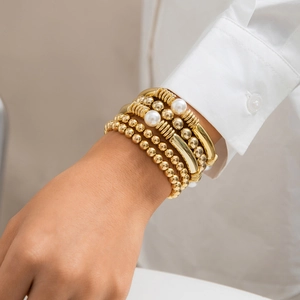 Gros plan d'un bracelet doré élégant avec perles métalliques et perles blanches au poignet