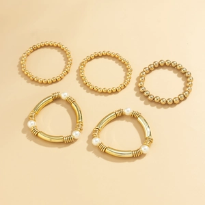 Détail d'un ensemble de 5 bracelets dorés avec tubes courbés et perles blanches nacrées