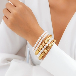 Détail d'un ensemble de bracelets multicouches avec perles blanches et perles dorées