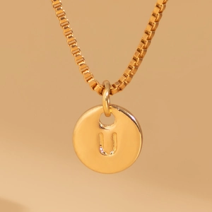 Detailed close-up of a gold box chain necklace with a round pendant engraved with letter U