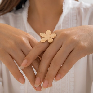 Exaggerated gold flower ring with matte metal petals worn on model's finger