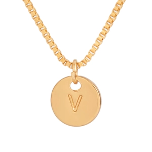 Detailed macro view of a polished gold-plated circular pendant with an engraved V initial