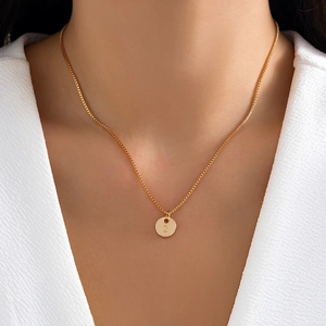 Close-up of a gold-plated round pendant necklace featuring an engraved letter Z on a model