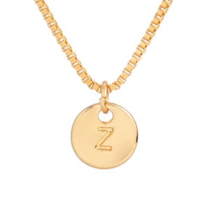 Detail shot of a gold round pendant necklace featuring a raised relief letter Z engraving