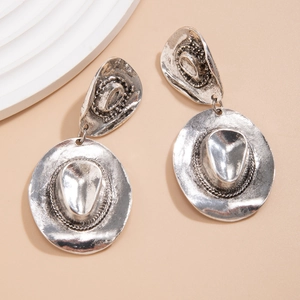Detailed view of silver cowboy hat earrings with vintage engraved metal texture