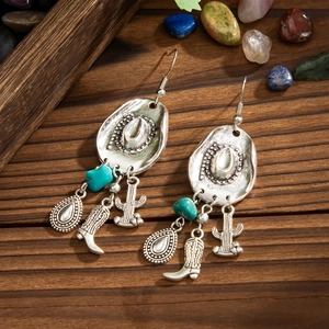 Detalle de pendientes de sombrero de vaquero con piedras turquesas sobre madera