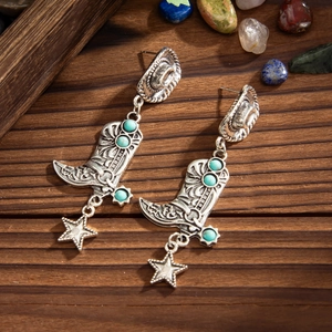 Detalle macro de pendientes de bota de vaquero plateados con turquesas y estrellas