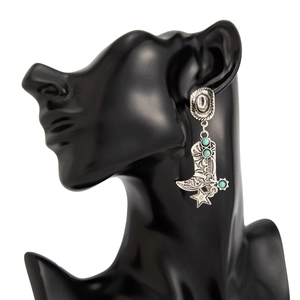 Detalle de pendientes de bota y sombrero vaquero con turquesa en expositor negro