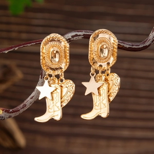 Detalle de los pendientes dorados estilo vaquero con colgantes de sombrero y bota