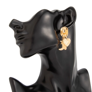 Detalle de pendientes dorados de sombrero y bota de vaquero con dije de corazón en maniquí