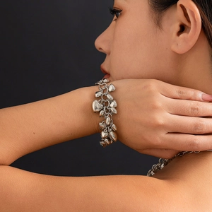 Detailopname van een zilveren bedelarmband met hartjes en dikke schakels om de pols