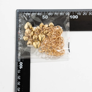 Gouden hartvormige hanger ketting met karabijnsluiting naast een meetliniaal