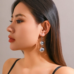 Close-up of a silver disco ball drop earring on a model with vintage aesthetic