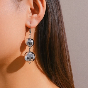 Close-up of shiny silver disco ball drop earrings with reflective faceted surface