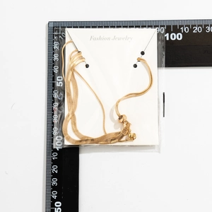 Flat lay of a gold snake chain necklace on a white card with a measurement scale