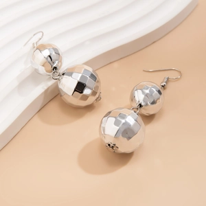 Detailed close-up of shiny silver double disco-ball earrings on a wavy white stand