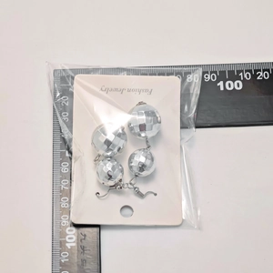 Detailed view of silver disco ball earrings with measurements on a black ruler