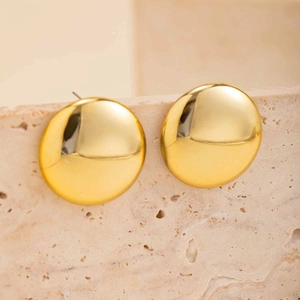 Close-up of polished gold round button stud earrings on natural stone background
