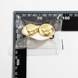 Close-up of 30mm golden polished sphere stud earrings on white card for size scale