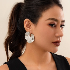 Close-up of geometric pleated fan-shaped silver earrings on model with metal texture